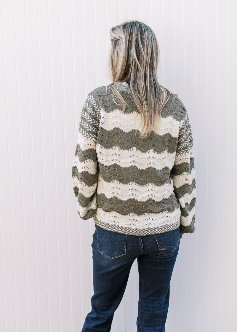 Back view of Model wearing an olive and cream cardigan with tie front and balloon long sleeves.