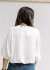 Back view of Model wearing a white polyester top with batwing short sleeves and a round neck. 