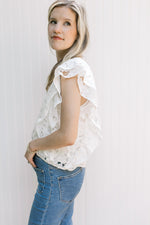 Side view of Model wearing a white top with lace flower cut out, layered sleeves and a square neck.