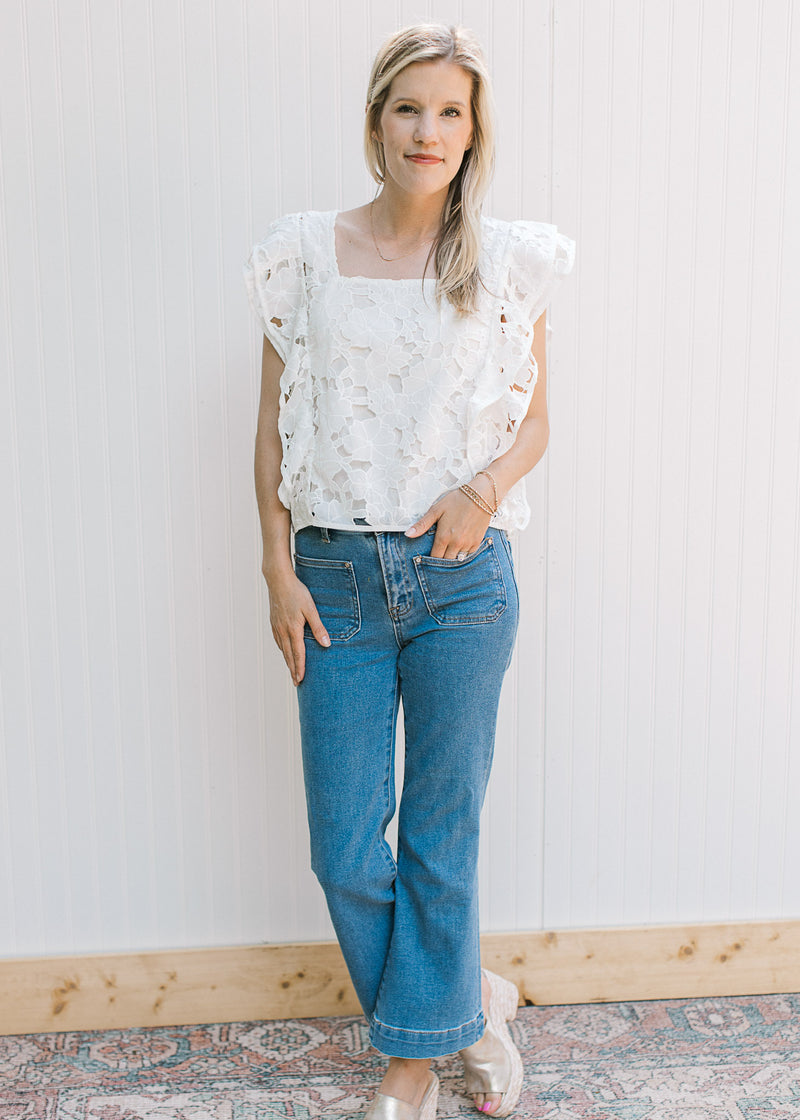 Model wearing jeans and wedges with a white lace floral top, layered cap sleeves and a square neck.