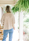 Back view of Model wearing a taupe knit sweater with embroidered daises and long sleeves. 