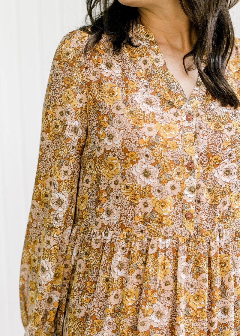 Close up view of v-neck with three button closure and sheer long sleeves on a chestnut dress. 