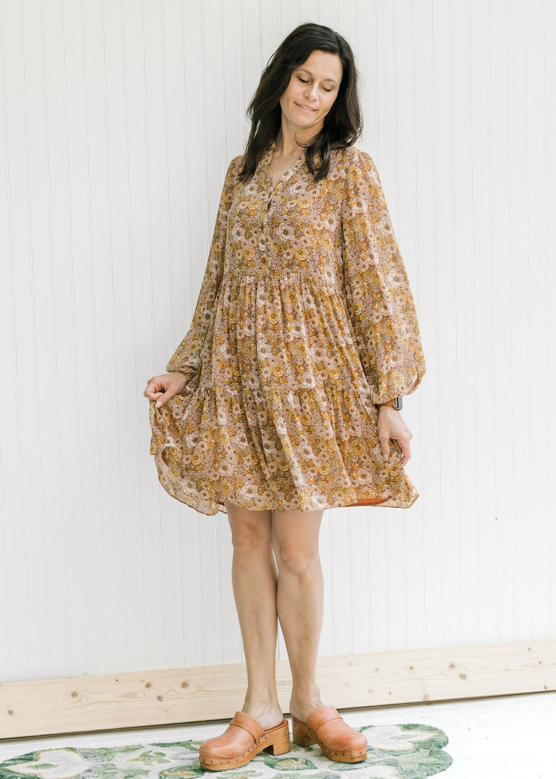Model wearing a tiered polyester above the knee dress with a chestnut color and floral design.