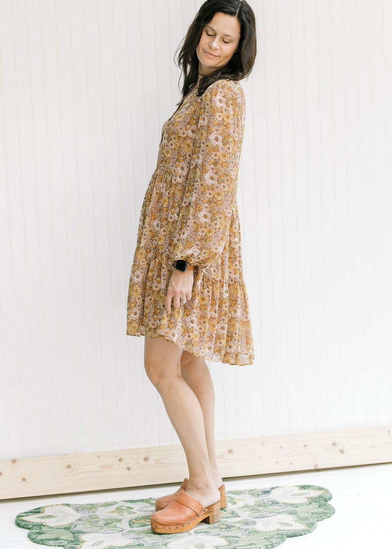 Model wearing a tiered, above the knee dress with a chestnut color and a natural floral pattern. 