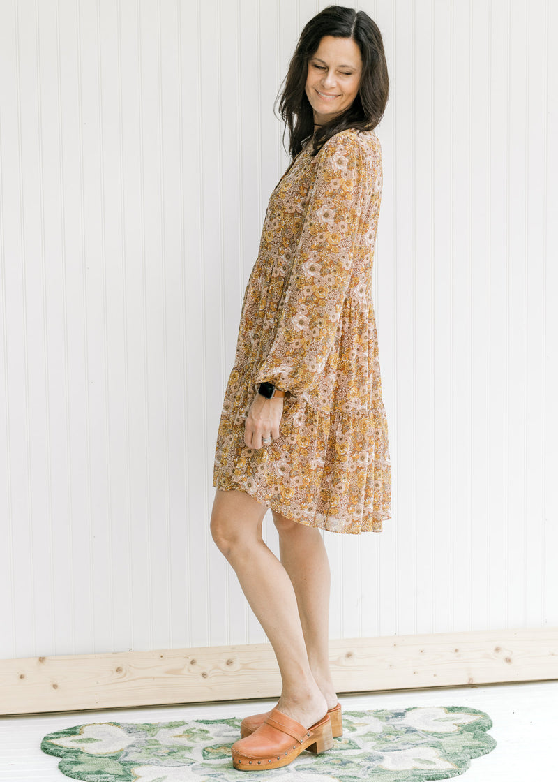 Model waring a long sleeve, above the knee dress with a chestnut color and a natural floral pattern.