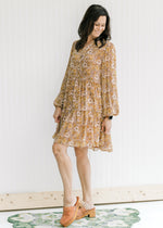 Model wearing heeled mules with a chestnut above the knee dress with a natural floral design.  