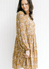 Model wearing a chestnut dress with natural floral pattern, sheer long bubble sleeves and tiers. 