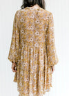 Back view of Model wearing a chestnut dress with a natural floral pattern and sheer long sleeves.