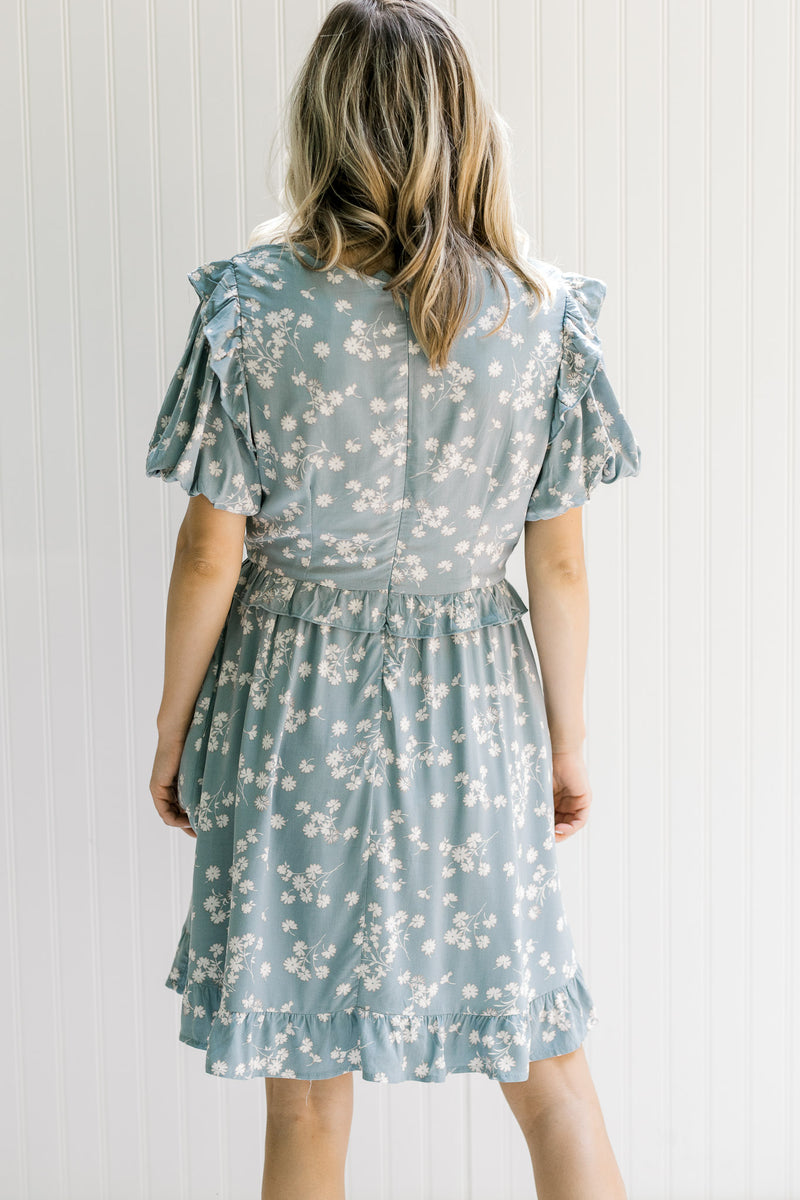 Back view of Model wearing a light blue dress with cream floral and bubble short sleeves.