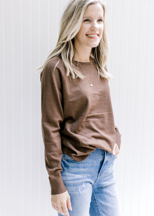Model wearing a lightweight brown sweater with a rolled hem at the neck and long sleeves. 
