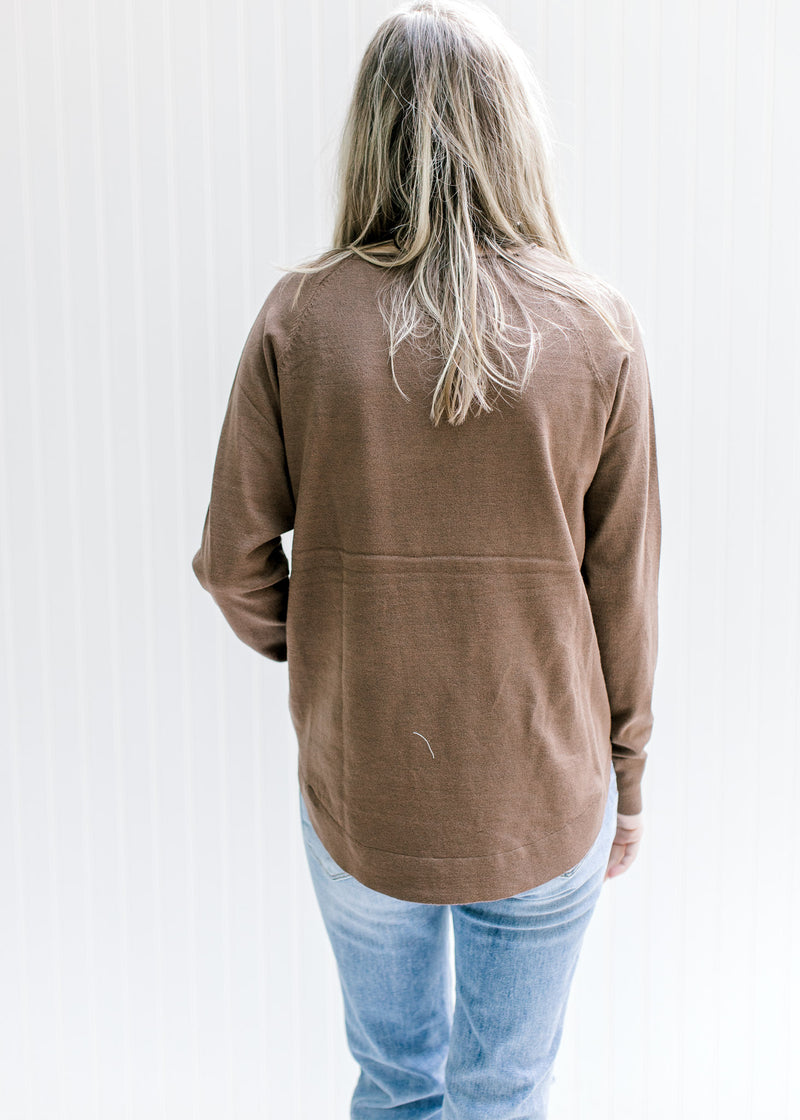 Back view of Model wearing a lightweight brown sweater with a rolled hem at neck and long sleeves.