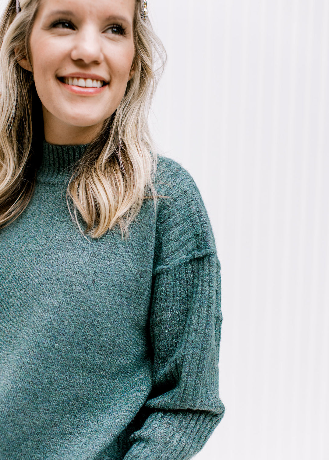 Close up of exposed hem and mock neckline on a soft forest sweater with long sleeves.