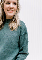Close up of exposed hem and mock neckline on a soft forest sweater with long sleeves.