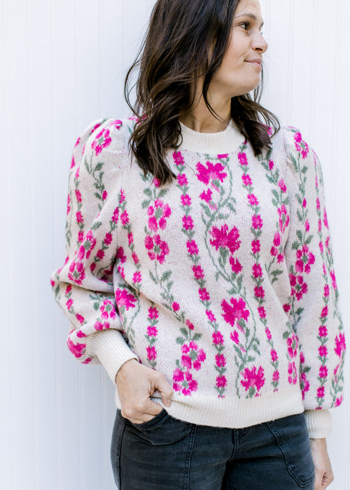 Model wearing a beige sweater with a pink floral pattern, long sleeves and pleated shoulders. 