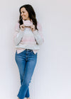 Model wearing a pink, taupe, aqua and cream ombre sweater with a turtle neck and long sleeves. 