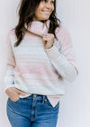 Close up of a sweater with a turtle neck and an ombre design of pink, taupe, aqua and cream.