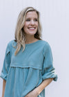 Close up view of fabric detail at arm and bust on a seafoam babydoll top with a round neck. 