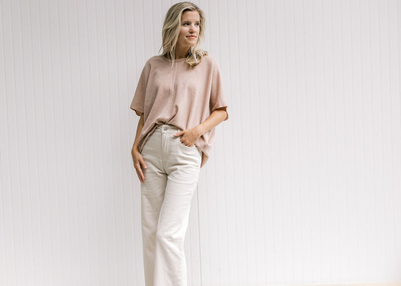 Model wearing sand colored pants comprised of cotton with a cropped fit and wide legs. 