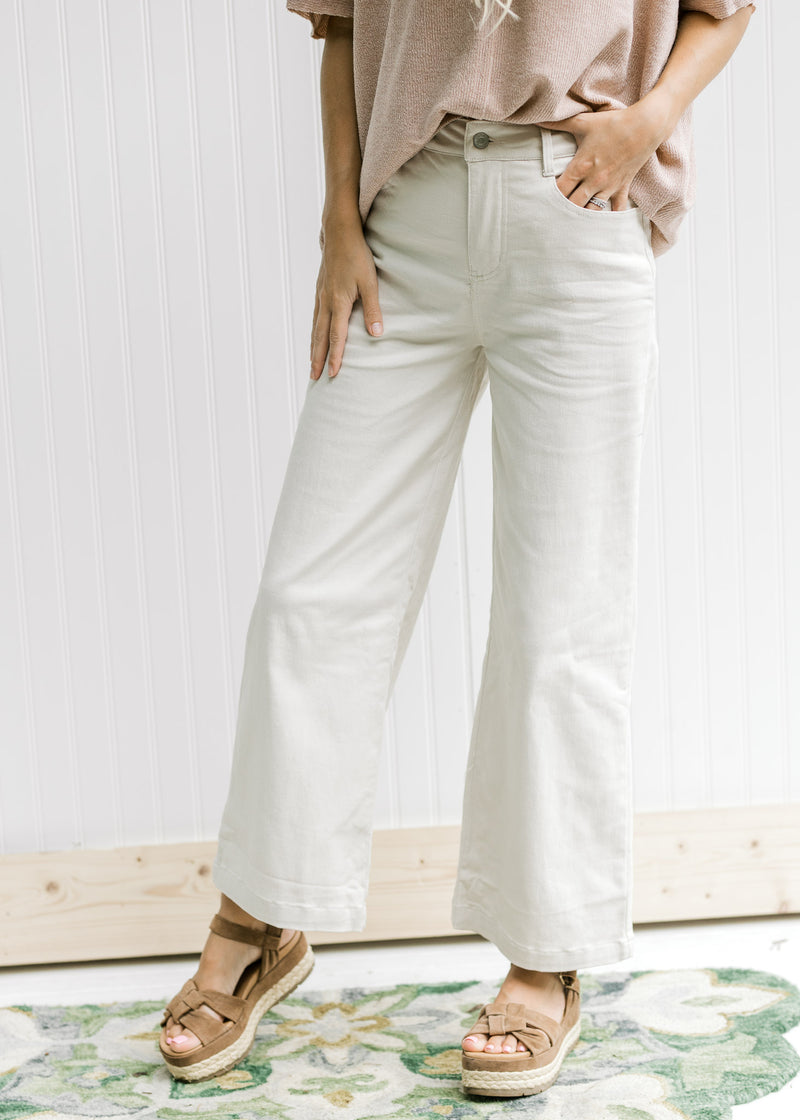 Model wearing sandals with sand colored cotton pants with a wide leg and a cropped fit. 
