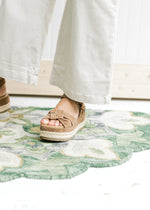 Close up of cropped fit on Model wearing sand colored pants comprised of cotton with a wide legs. 