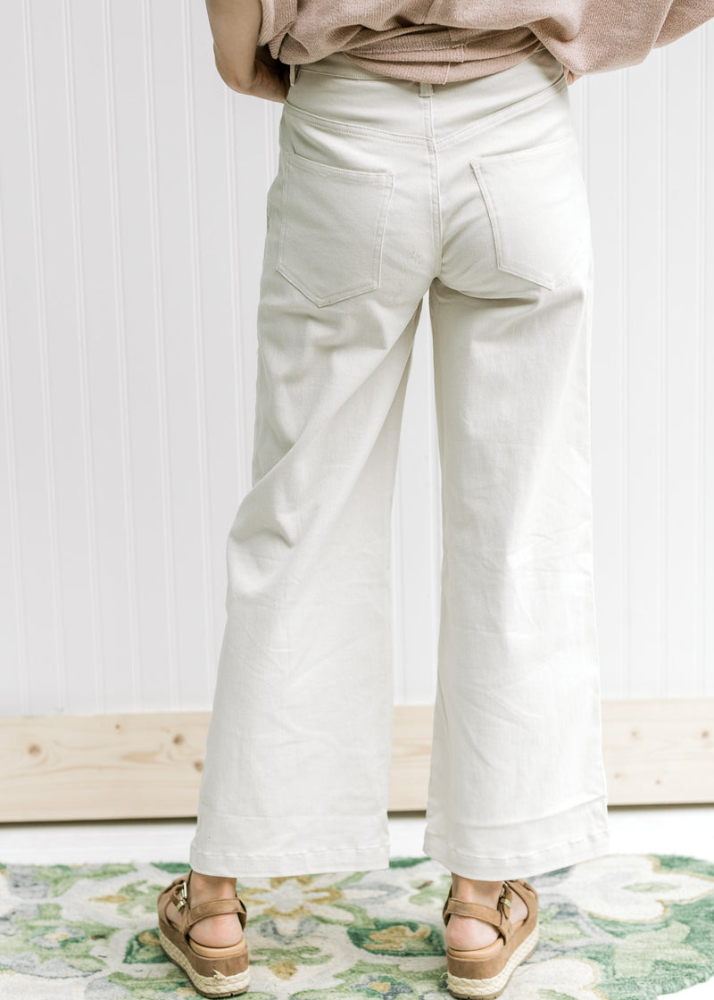 Back view of Model wearing sand colored pants comprised of cotton with a cropped fit and wide legs. 
