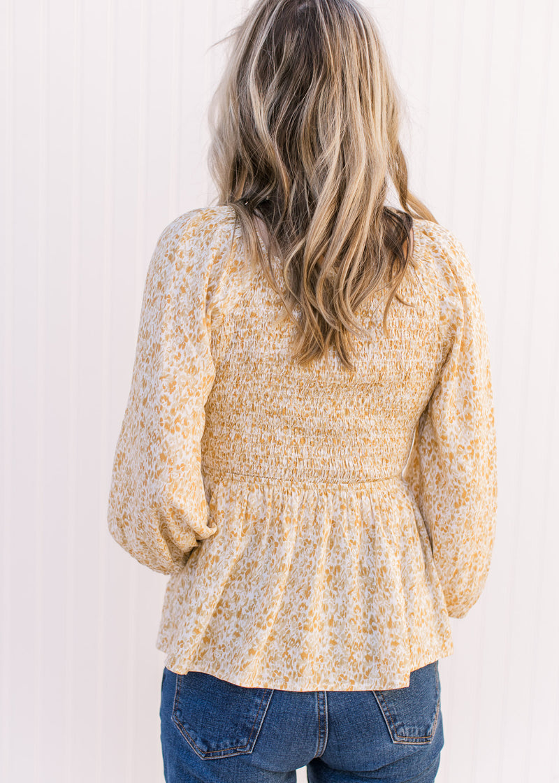 Back view of Model wearing a cream top with yellow, cream and gold ditsy floral and smocked bodice.