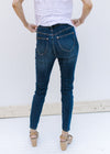 Back view of Model wearing medium wash skinny jeans that are high wasted with an elastic waistband. 