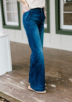 Side view of Model wearing wide leg, dark wash, jeans. 