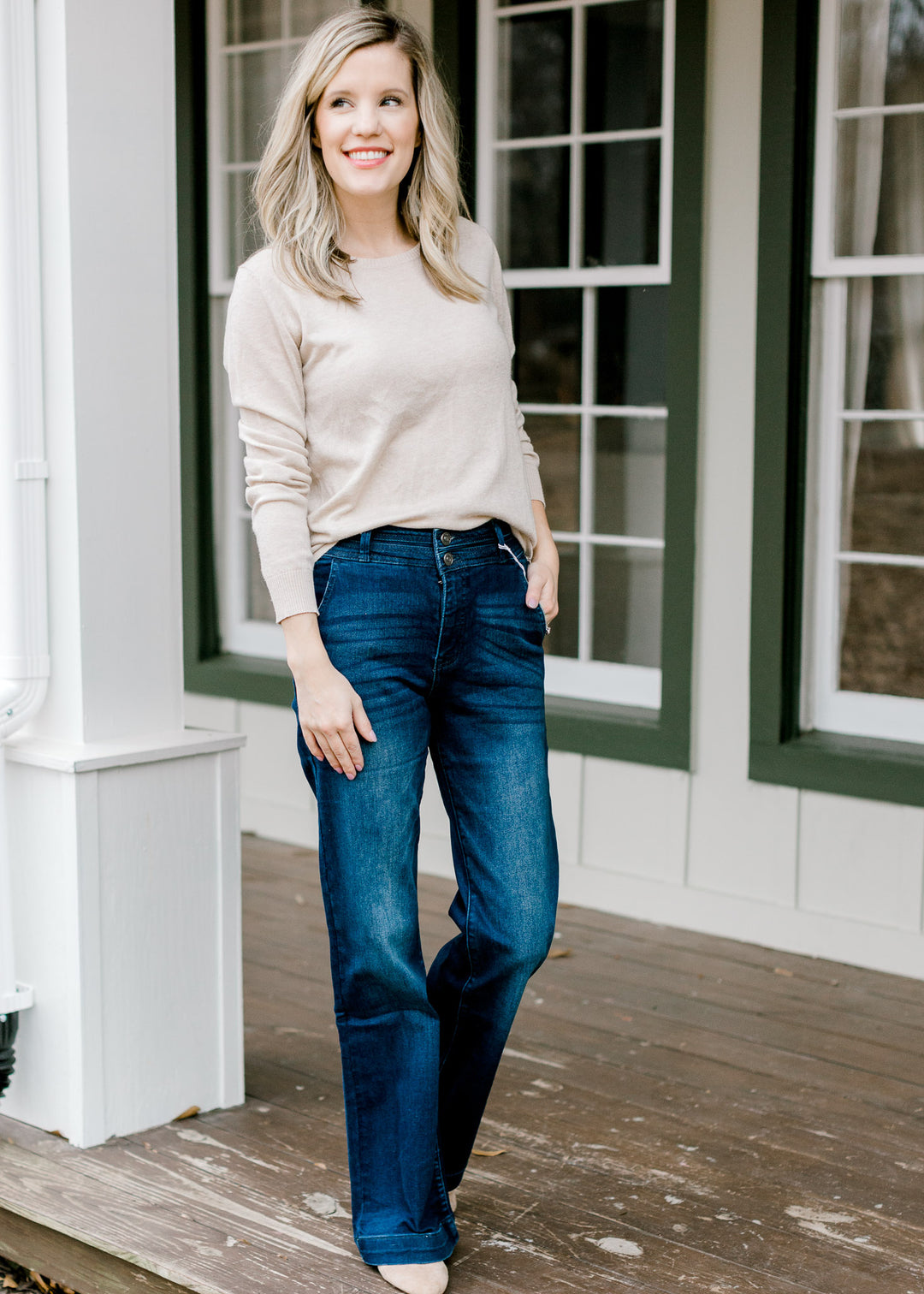 Model wearing wide leg, dark wash, jeans with a tan sweater. 