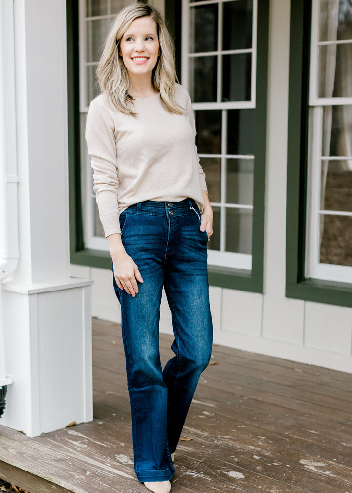 Model wearing wide leg, dark wash, jeans with a tan sweater. 