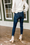 Back view of Model wearing dark wash skinny jeans with a fray hem.
