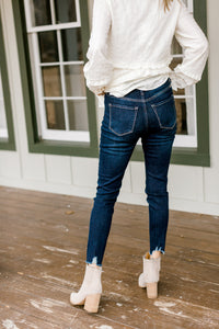 Back view of Model wearing dark wash skinny jeans with a fray hem.