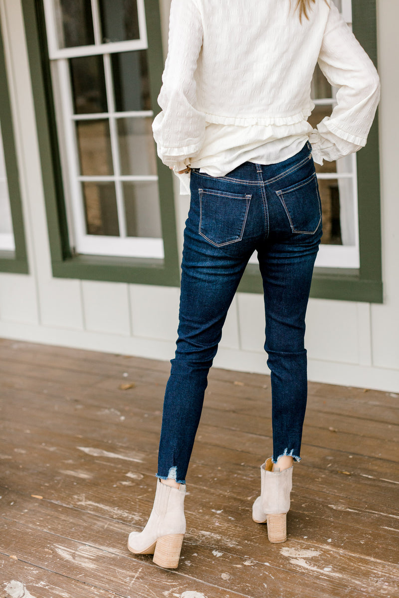 Back view of Model wearing dark wash skinny jeans with a fray hem.