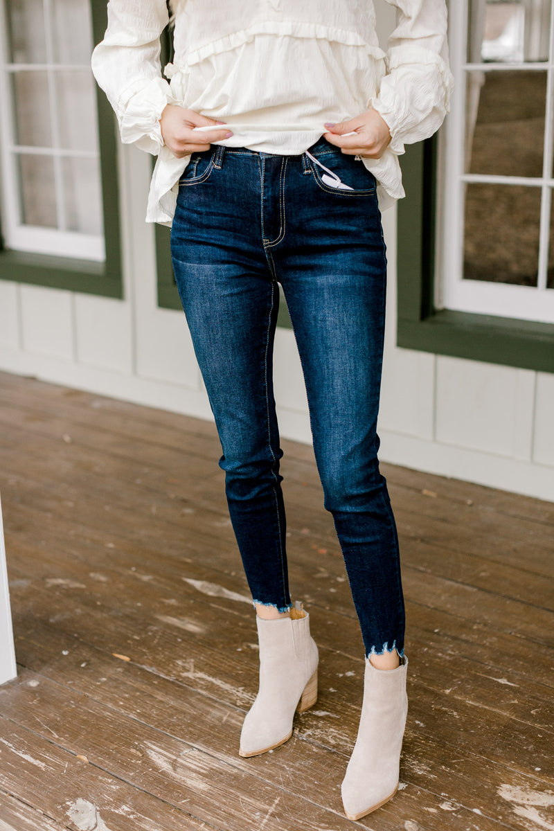 Model wearing booties with dark wash skinny jeans with a fray hem. 