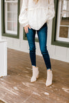 Model wearing dark wash skinny jeans with a fray hem. 