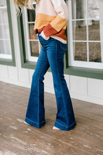 Side view of Model wearing flare, hi-rise jeans. 