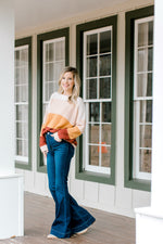 Blonde model wearing a color block weather with flare, hi-rise jeans. 