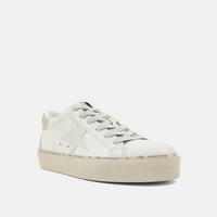 Front angle view of bone colored shoes with silver strings, a round toe and a star on the side. 