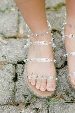 Clear lucite with silver stud sandals on foot.