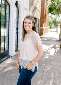 Brunette model wearing cream colored cut lace top.