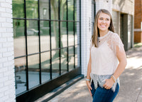 Brunette model wearing cream colored cut lace top and jeans.