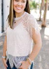 Close up of Brunette model wearing cream colored cut lace top.