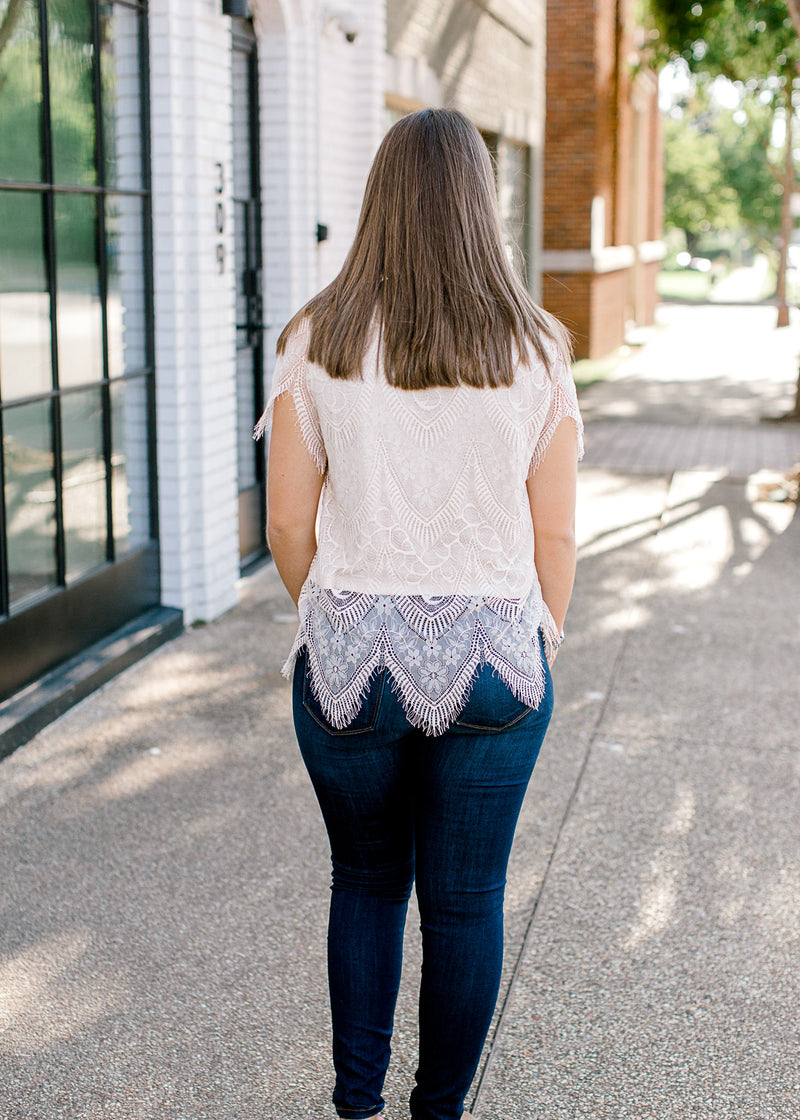 BAck view of Brunette model wearing cream colored cut lace top.