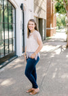 Brunette model wearing cream colored cut lace top, jeans, and sandals.