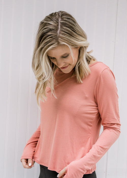 Blonde model wearing an apricot color long sleeve athletic top.