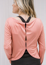 Back view of Blonde model wearing an apricot athletic top with detail openings.