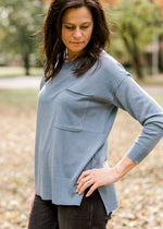 Brunette model wearing a long sleeve, ash blue sweater