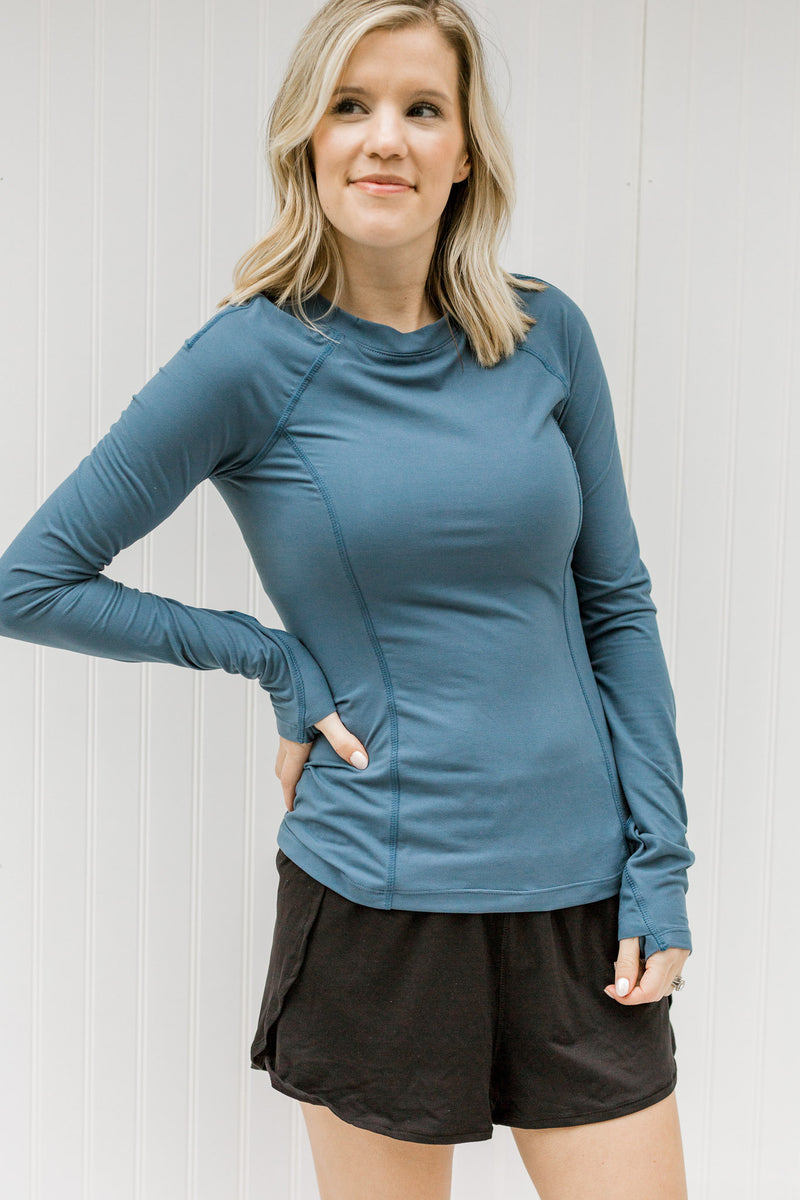 Blonde model wearing blue fitted athleisure top with black shorts.