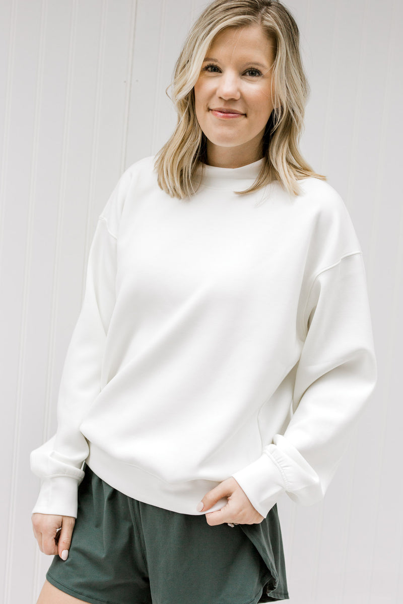Blonde model wearing a cream sweatshirt.