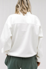 Back view of Blonde model wearing a cream sweatshirt.